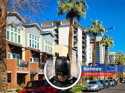 Gotham City skyline with a looming shadow, symbolizing the economic pressures affecting housing.